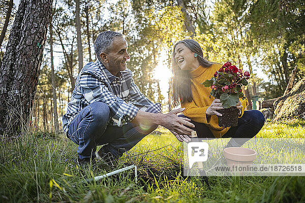 Happy mature couple planting flower in natural garden