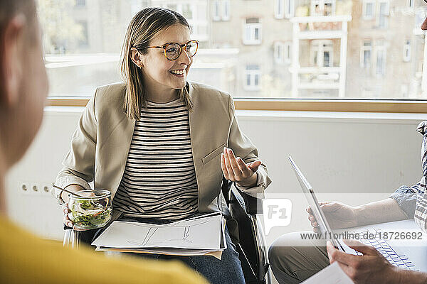 Smiling young businesswoman in wheelchair having a meeting in office
