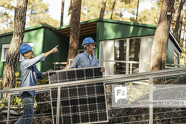 Photovoltaic technicians carrying solar panel together