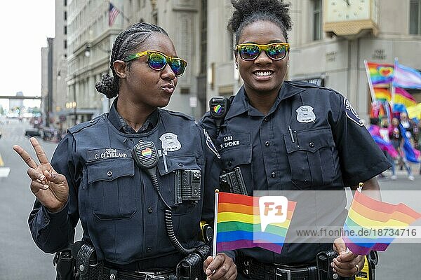 Schwule  lesbische  bisexuelle und transsexuelle Aktivisten und ihre Verbündeten marschieren auf der Motor City Pride Parade für Gleichberechtigung. Zwei Polizistinnen aus Detroit tragen Regenbogenflaggen  Detroit  Michigan  USA  Nordamerika