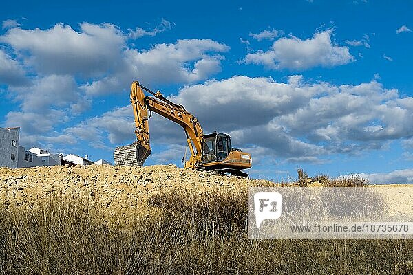 Large yellow excavator working on the construction site moving earth
