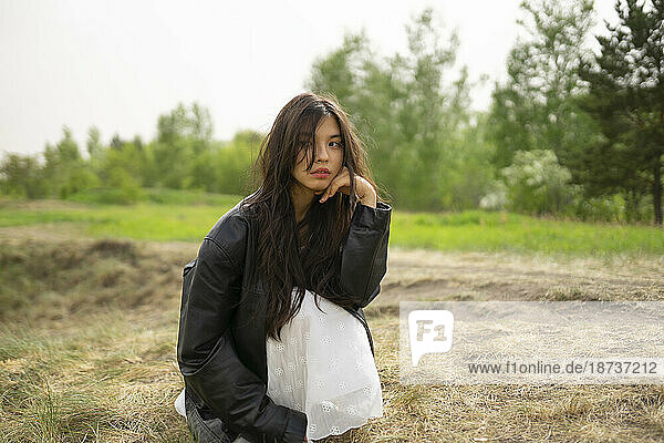 Portrait of teenage girl (16-17) crouching in nature