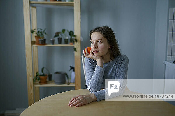 Portrait of thoughtful woman with apple in hand
