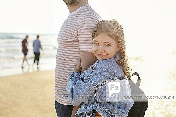 Liebevoller Vater umarmt seine entzückende kleine Tochter am Strand  Vater und Kind verbringen Zeit im Freien zusammen  sonniges Meer im Hintergrund. Parenting Konzept