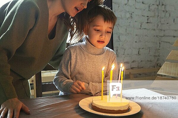 Kleiner kaukasischer Junge im Vorschulalter bläst Kerzen auf einem selbstgebackenen Geburtstagskuchen zu Hause aus  ein Kind wünscht sich etwas bei einer Geburtstagsfeier mit seiner Familie. Selektiver Fokus