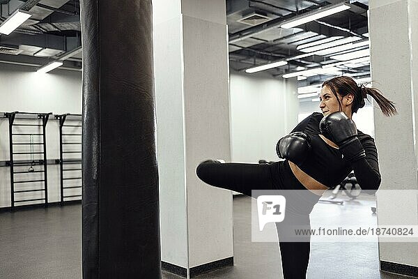 Starke lateinischen Boxen Frau Sprung Kick zu riesigen Boxsack im Fitnessstudio. Athletische Mädchen Ausbildung Muay Thai Boxen für Bodybuilding und gesunden Lebensstil Konzept. Workout im Sportverein