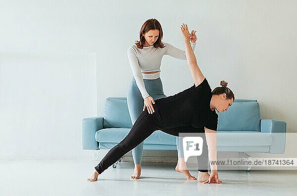 Erwachsene Frau hilft Frau in Sportkleidung mit Yogapose und Stretching Arme