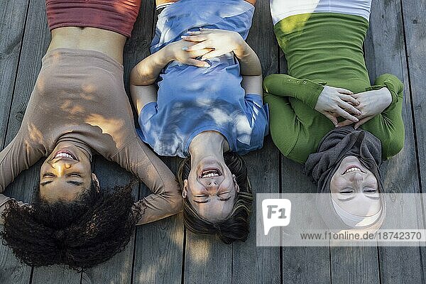 Multirassische junge Teenager Freundinnen ruhen sich nach dem Sporttraining im Park aus  lachen und haben Spaß zusammen. Diversität  Sport und Freundschaft Konzept