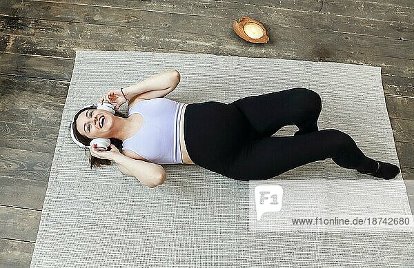 Bild einer erstaunlichen gesunden schwangeren Frau drinnen zu Hause auf dem Boden durch Sofa hören Musik mit Kopfhörern. Glückliche Schwangerschaft Konzept