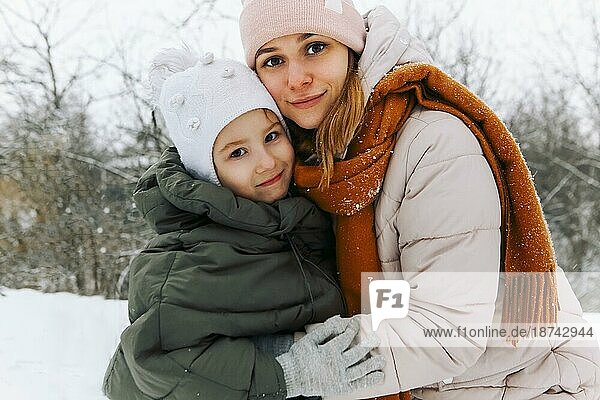 Lovely glückliche Familie Mutter und kleines Mädchen Tochter  die Spaß auf verschneiten Wetter im Freien  freudige spielerische Mutter mit Kind umarmen  während Zeit aktiv im Winter Park auf kalten frostigen Tag