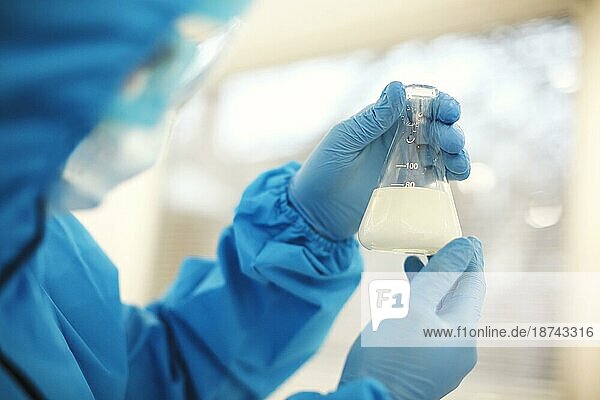 Wissenschaftlerin im Labor  die Proben in einem Reagenzglas untersucht  arbeitet in einem afrikanisch amerikanischen Frauen Genlabor und trägt geschützte Kleidung