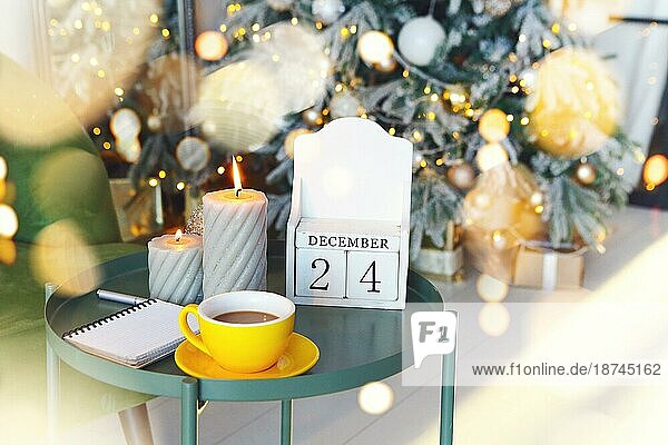 Heiligabend Datum. 24. Dezember auf hölzernen Kalender stehen auf kleinen Tisch mit brennenden Kerzen im Wohnzimmer  selektiven Fokus. Weihnachten und Neujahr Konzept