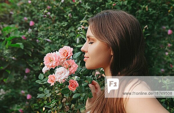 Mode Outdoorfoto von schönen sexy Frau mit dunklen Haaren posiert in Blüte Garten mit Rosen Sträucher