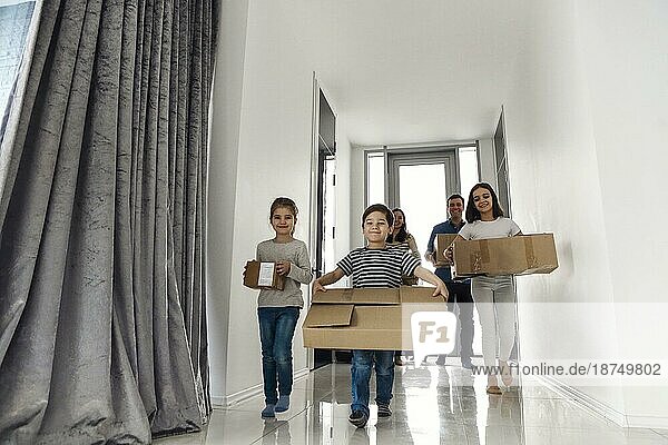 Glückliche Familie läuft im Flur. Lustige Kinder springen mit Karton Box  Eltern lachen  spielen mit Kindern Spaß haben zusammen in ein neues Haus zu bewegen. Hypothekendarlehen und verlagern Konzept