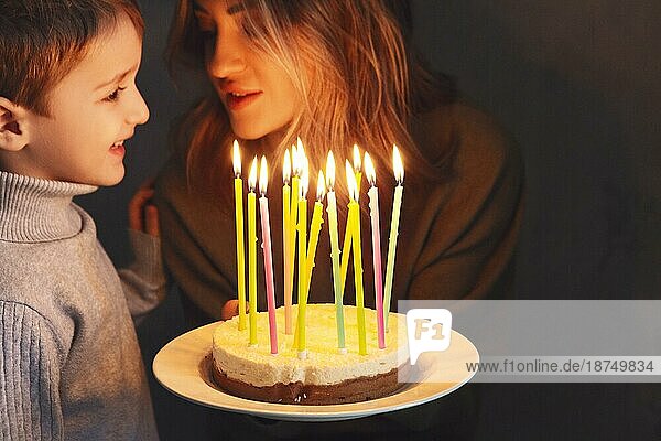 Kleiner kaukasischer Junge im Vorschulalter bläst Kerzen auf einem selbstgebackenen Geburtstagskuchen zu Hause aus  ein Kind wünscht sich etwas bei einer Geburtstagsfeier mit seiner Familie. Selektiver Fokus