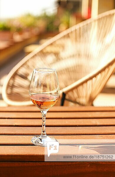 Glas Weißwein auf rustikalen Holztisch und Blumentöpfe auf der Terrasse außerhalb mit Weinberg Hügel Landschaft am sonnigen Tag Morgen im Sommer Zeit