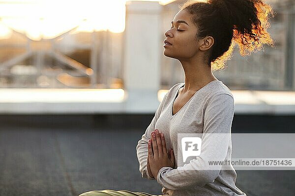 Ausgeschnittenes Foto einer Frau  die im Lotussitz auf einer Matte sitzt und Yoga praktiziert  eine Frau  die die Namaste Geste macht  während sie drinnen meditiert. Meditation und Achtsamkeit Konzept