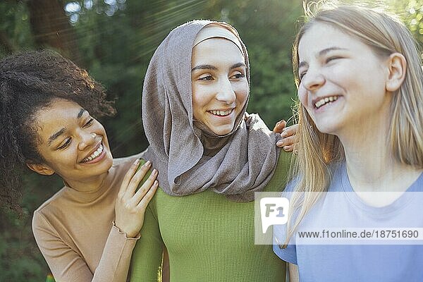 Multiracial junge Teenager weibliche Freunde zu Fuß in den Park lachen und Spaß haben zusammen. Diversität und Freundschaft Konzept