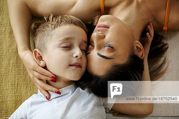 Blick von oben auf junge positive Familie Mutter und Sohn lachen und umarmen  während auf dem Bett liegend und genießen glückliche Momente zusammen  niedlichen kleinen Jungen verbringen Wochenende Tag mit Mama