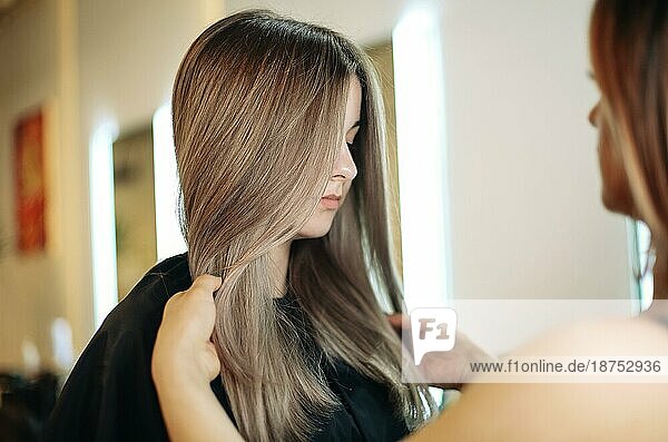 Professionelle Friseurin schmiert Farbstoff auf das Haar einer Frau bei der Arbeit im Schönheitssalon