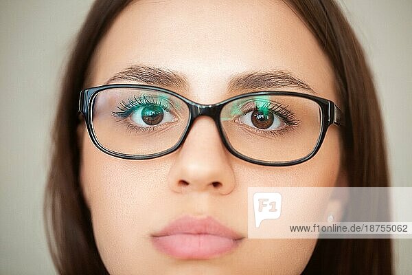 Nahaufnahme von Ernte junge brünette Frau mit braunen Augen und in Brillen auf grauem Hintergrund