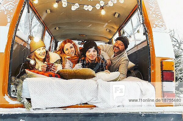 Glückliche Familie von Reisenden in Minivan liegen zusammen bei offenen hinteren Türen und lächelnd in die Kamera. Fröhliche Gruppe von Menschen Reisen Winter verschneite Natur  verbringen Neujahr und Weihnachten Urlaub im Freien
