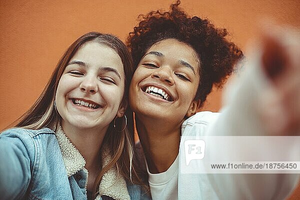 Selbstporträt von zwei glücklichen  fröhlichen Teenagermädchen verschiedener Rassen  die in die Kamera lächeln und die Freundschaft genießen  multiethnische beste Freundinnen  die ein Selfiefoto machen und Spaß haben  während sie Zeit miteinander verbringen