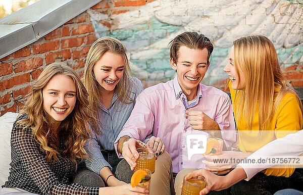Gruppe von jungen glücklichen Menschen Freunde trinken Fruchtcocktails zusammen auf Haus Terrasse  lächelnd und lachend  Gruppe von Jugendlichen Ausdruck positiver Emotionen und Spaß haben auf der Party