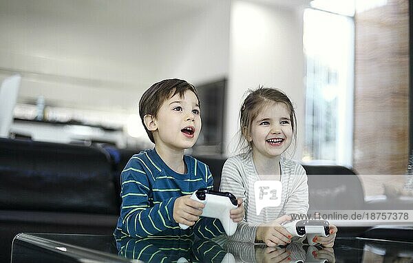 Fröhliche Kinder mit Spielcontrollern spielen zu Hause Videospiele. Freizeit für Kinder