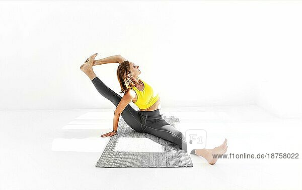 Seitenansicht einer ruhigen Frau in Sportkleidung  die Yoga praktiziert  während sie auf den Armen auf der Matte balanciert und wegschaut