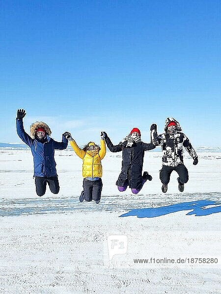 Gruppe von glücklichen Touristen Freunde springen auf dem Hintergrund der Eis Wintersee Baikal am sonnigen Tag. Winter Baikalsee  Russland. Konzept der Freiheit  Reisen und Glück