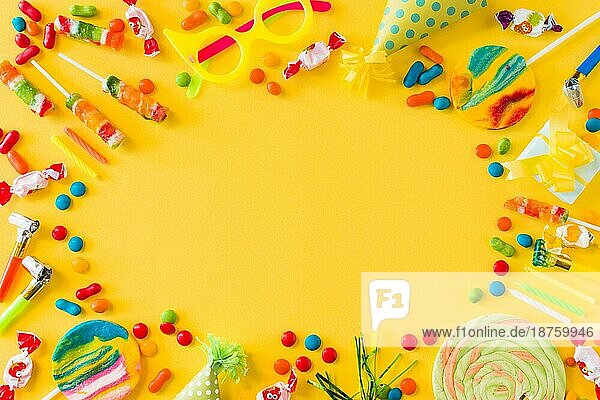 Hohe Winkelansicht Bonbons Lutscher Kerzen Party Blower gelbe Oberfläche. Hohe Auflösung Foto
