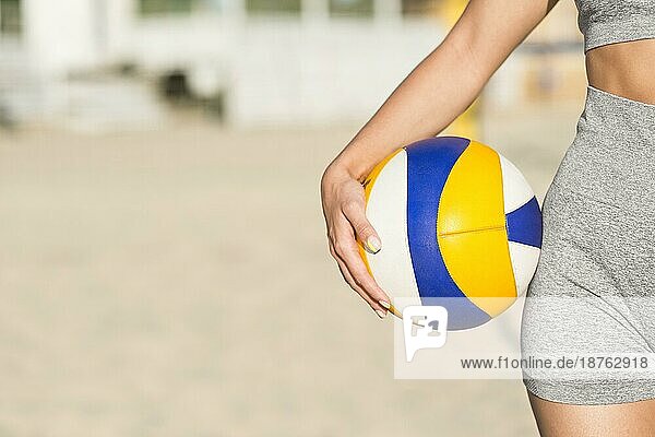 Vorderansicht einer Volleyballspielerin am Strand  die einen Ball hält  mit Kopiervorlage