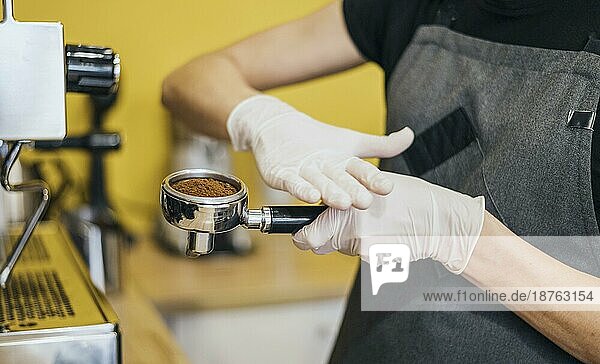 Seitenansicht Barista mit Latexhandschuhen bei der Vorbereitung der Kaffeemaschine. Foto mit hoher Auflösung