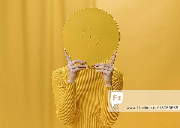Frau hält Vinyl vor Gesicht gelbe Szene