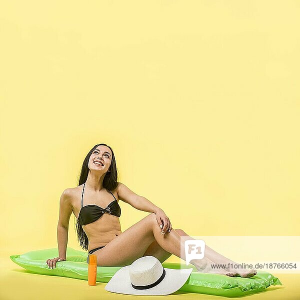 Frau schwarzer Badeanzug sitzend Wasser Matratze lächelnd