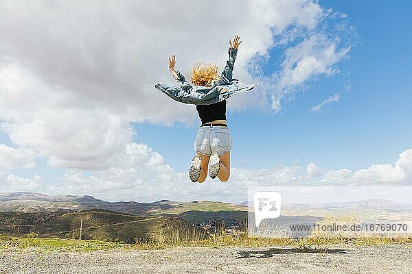 Frau springt vor Freude auf einem Hügel. Foto mit hoher Auflösung