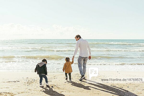 Mann mit Kleinkindern geht Richtung Meer. Schönes Foto