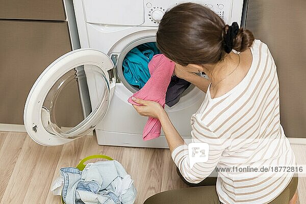 Dame nimmt Kleidung aus der Waschmaschine. Foto mit hoher Auflösung