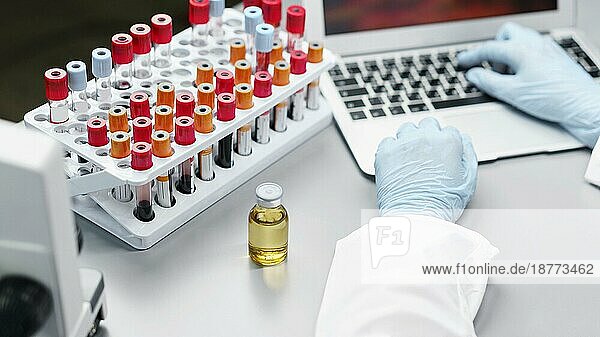 Forscherin im Labor mit Impfstoffflasche und Reagenzgläsern