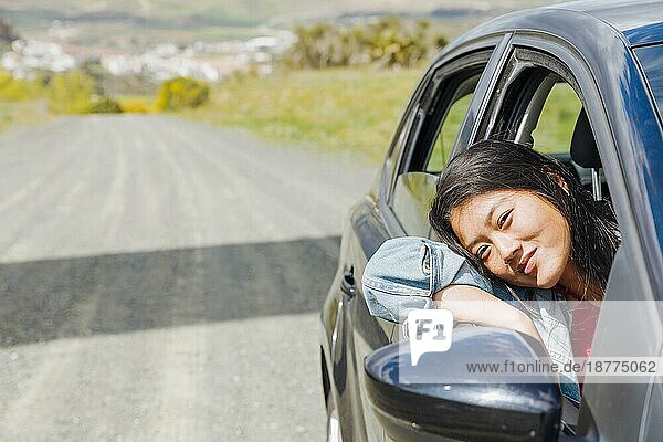 Lächelnde asiatische Frau schaut aus dem Auto