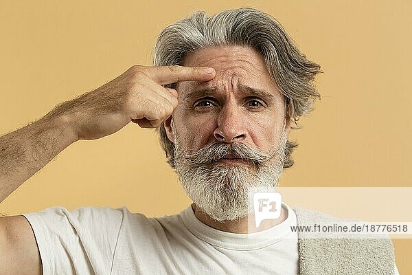 Vorderansicht älterer Mann mit Bart  der auf Falten zeigt