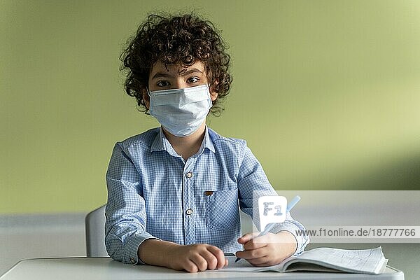 Vorderansicht Junge mit medizinischer Maske Schule während Pandemie. Schönes Foto