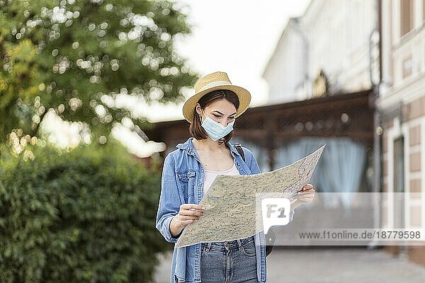 Reisender mit Hut und medizinischer Maske  der die Karte kontrolliert