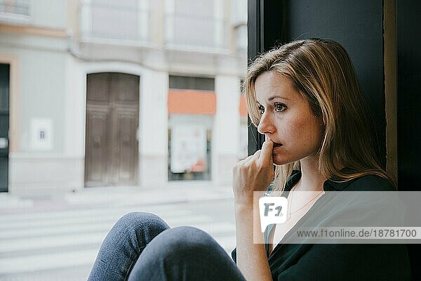 Frau denkt in der Nähe des Fensters eines Cafés