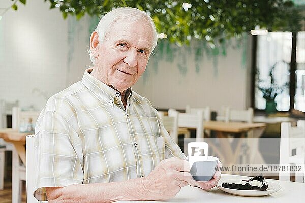Älterer Mann trinkt Tee und schaut in die Kamera