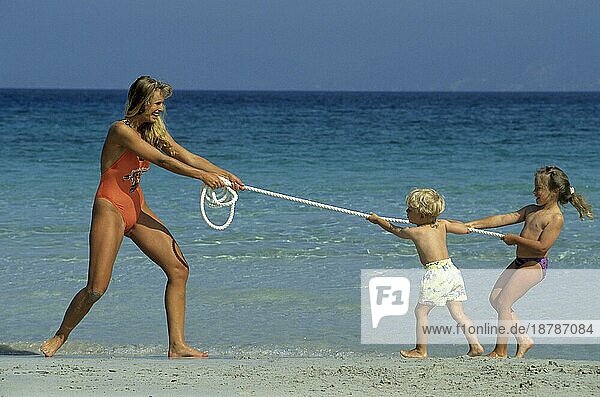 Frau mit 2 Kindern am Strand  tauziehen