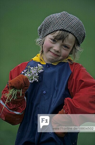 Junges kleines Mädchen 7  8  9  10 Jahre alt mit Wiesenblumen  Winterkleidung  Mütze  Schal  Handschuhe  dicke Jacke
