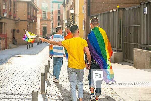 Gay Pride Party in der Stadt  Paare von Männern zu Fuß Rücken an Rücken in Richtung der Demonstration mit Regenbogenfahnen  lgbt Konzept