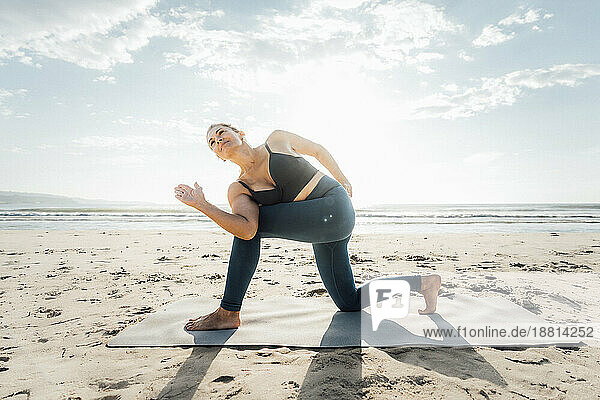Frau trainiert auf Matte am Strand